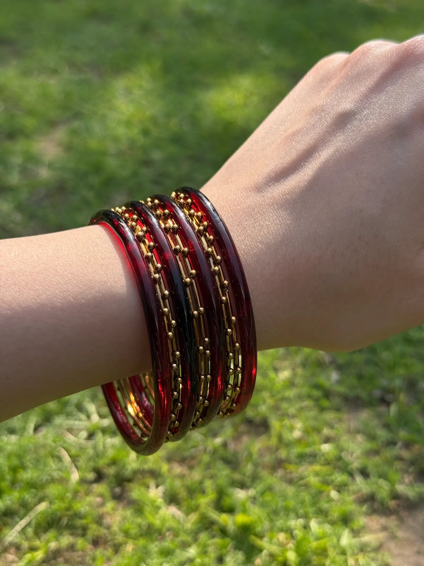 Stacked maroon and golden bangle set displayed from multiple angles